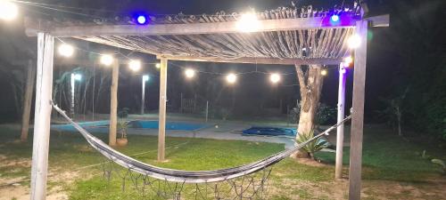 a hammock under a pergola in a yard at night at Recanto agape chalés e cabana in Rosas