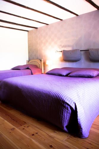 a large bed with purple sheets and pillows on it at Gîte Le Bol d'Air in Puilly-et-Charbeaux