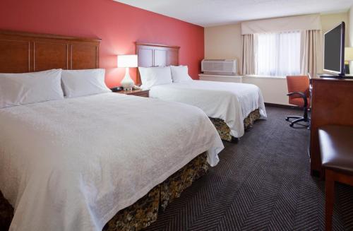 two beds in a hotel room with red walls at Best Western Plus St. Paul North/Shoreview in Shoreview