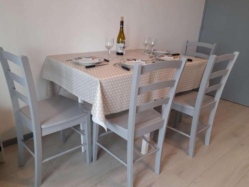 - une table à manger avec des chaises et une bouteille de vin dans l'établissement Appartement refait à neuf avec loggia et parking, à 2 pas de la plage et des commerces - FR-1-712-7, à Villers-sur-Mer