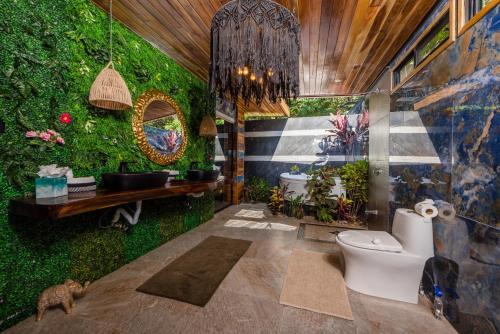 baño con una pared verde con plantas en Ocho Artisan Bungalows, en Tamarindo