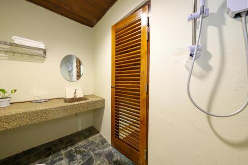 La salle de bains est pourvue d'une douche et d'une porte en bois. dans l'établissement Ivory Boutique Hotel, à Rawang