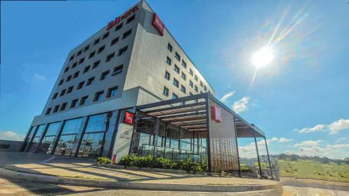 a hotel building with the sun in the sky at ibis Lavras in Lavras