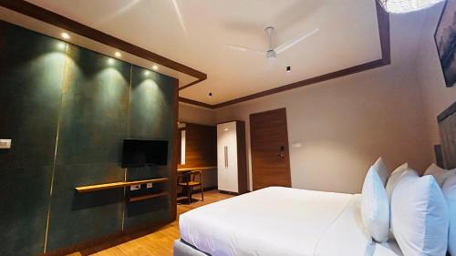 a hotel room with a bed and a tv at CMK HABITAT CENTRE in Ernakulam