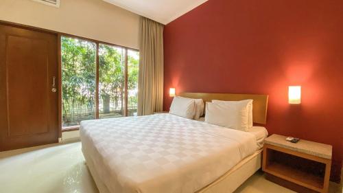 a bedroom with a large bed and a large window at Lorin Dwangsa Solo Hotel in Solo