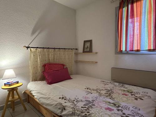 - une chambre avec un lit doté d'un oreiller rouge et d'une fenêtre dans l'établissement Bel appartement 2 pièces à Banyuls-sur-Mer, terrasse, parking privé, à 300m de la plage - FR-1-225C-144, à Banyuls-sur-Mer