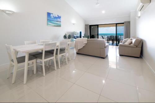 a dining room and living room with a table and chairs at Whitsunday Beachfront Apartment on Coral Esplanade in Cannonvale