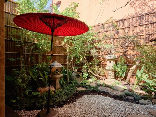 a red umbrella sitting in the middle of a garden at KONJAKUSO Nara Naramachi "MUSHIBUROYA" Sauna Villa in Nara