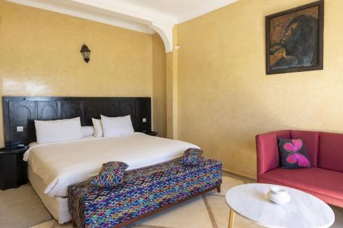 1 dormitorio con 1 cama y 1 sofá rojo en Hôtel Calipau Riad Maison d'Hôtes, en Dakhla