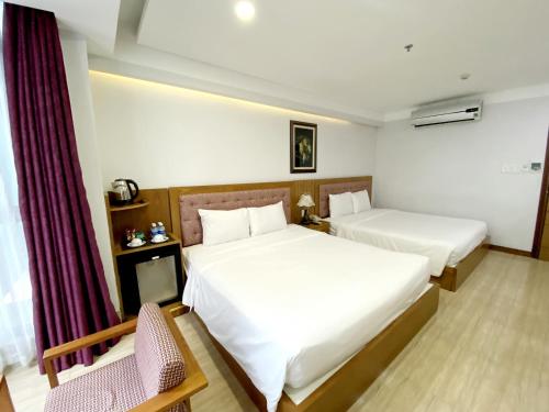 a hotel room with two beds and a chair at Happy Light Central Nha Trang in Nha Trang