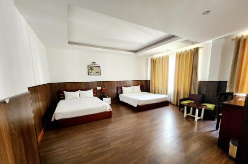 a hotel room with two beds and a desk at Happy Light Central Nha Trang in Nha Trang