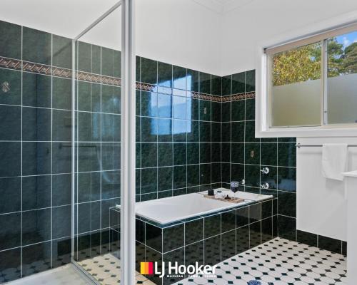 un bagno piastrellato verde con lavandino e doccia di The Moorings a Iluka