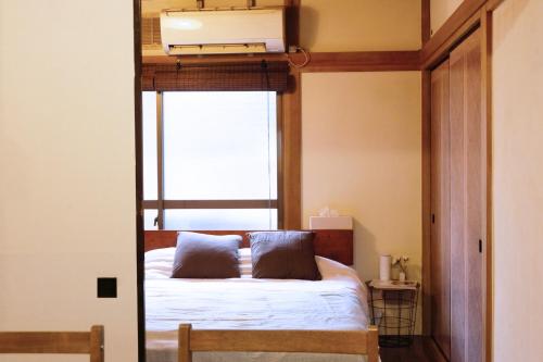 1 cama con 2 almohadas en una habitación con ventana en Daiichi Mitsumi Corporation - Vacation STAY 14914, en Musashino
