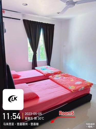 two beds in a room with a window at EMERALD VILLA HOMESTAY DUNGUN in Batu Lima