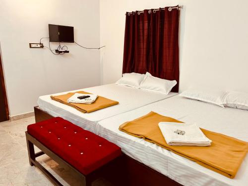 a bedroom with two beds and a red bench at DE Villa Breeze @ Beach side in Pondicherry