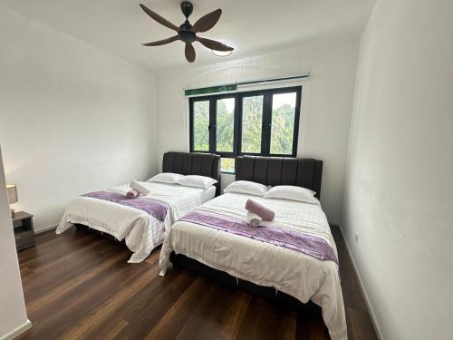two beds in a room with a ceiling fan at JOMSTAY Sunway Onsen Suites Ipoh - Lost World of Tambun Ipoh Waterpark in Tambun