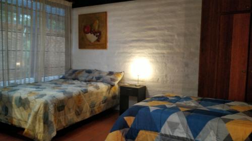 a bedroom with two beds and a lamp on a table at Casa del Aguacate Cumbaya - Tumbaco in Cumbayá