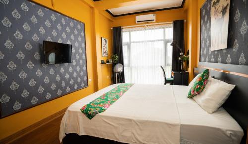 a bedroom with a bed with yellow walls and a window at VietHouse Homestay Ha Long in Ha Long