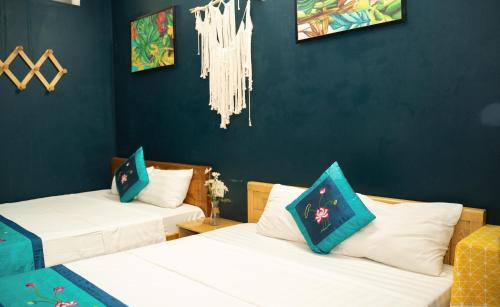 two beds in a room with blue walls at VietHouse Homestay Ha Long in Ha Long