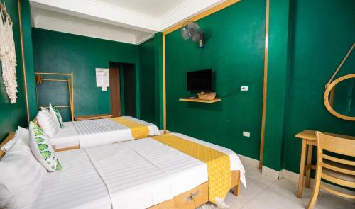 two beds in a room with green walls at VietHouse Homestay Ha Long in Ha Long