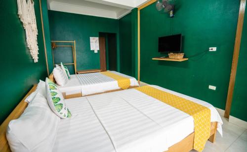 two beds in a room with a green wall at VietHouse Homestay Ha Long in Ha Long