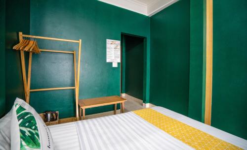 a bedroom with a green wall with a bed and a chair at VietHouse Homestay Ha Long in Ha Long