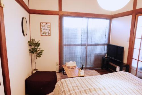 1 dormitorio con 1 cama, TV y ventana en Daiichi Mitsumi Corporation - Vacation STAY 15355, en Musashino