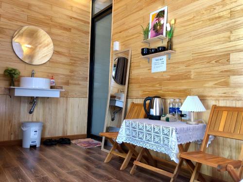 a room with a table and a sink and wooden walls at Nhà Bắp in Da Lat