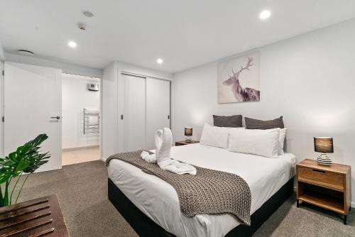 a bedroom with a large white bed and a room at Lakeside Living - Modern 2-Bedroom Apartment in Queenstown