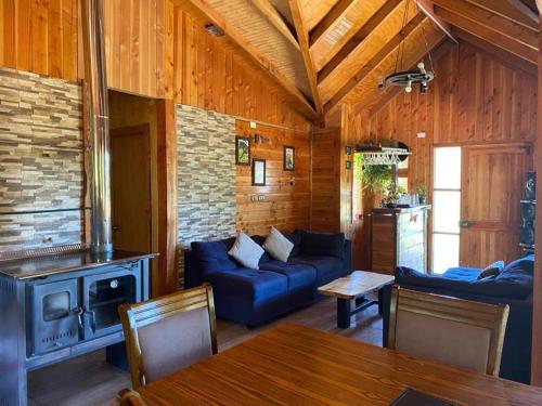 a living room with a blue couch and a stove at Vista verde Llonquén in Liquiñe