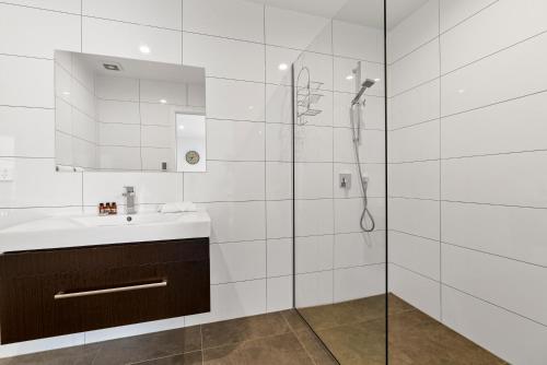 Un baño blanco con lavabo y ducha en Alpine Retreat - Panoramic Views, en Queenstown