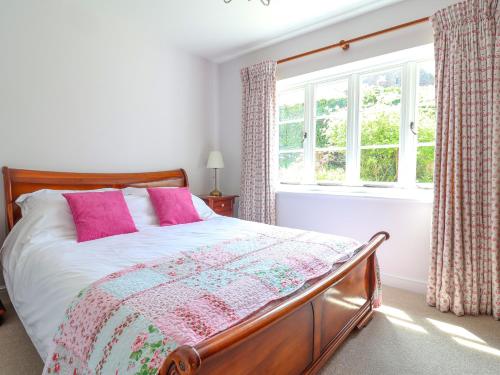 a bedroom with a bed with pink pillows and a window at Questant Lodge in Sidmouth