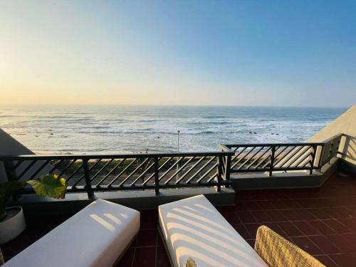 a balcony with two white benches and the ocean at Chic Bohemian Hideaway in Umdloti