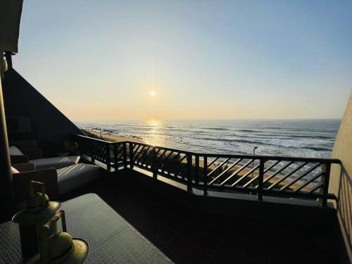 a balcony with a view of the ocean at sunset at Chic Bohemian Hideaway in Umdloti