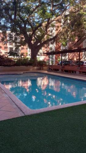 a swimming pool with a tree and a building at TLT Condotl E-208 -Near Airport at Kiener Hills Condominium in Mactan