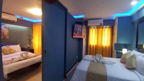 a bedroom with two beds and a tv on the wall at TLT Condotl E-208 -Near Airport at Kiener Hills Condominium in Mactan