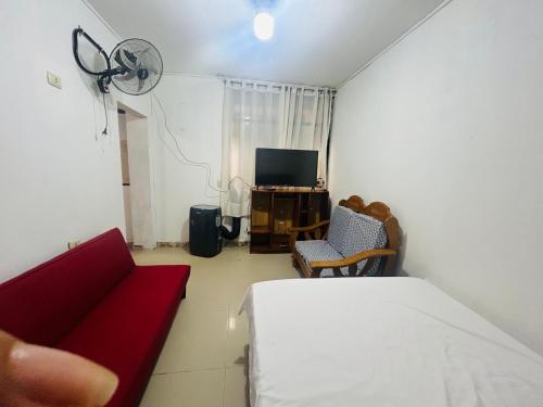Mini depa de una habitación في بوكالبا: غرفة معيشة مع أريكة حمراء وتلفزيون