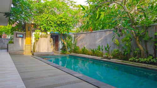 a swimming pool in a yard with trees at Dirga's House Sanur View by EPS in Sanur