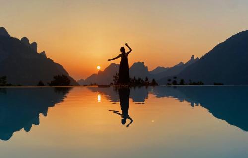 une femme debout sur l'eau au coucher du soleil dans l'établissement XMAN Valley Sunrise Resort, à Zhangjiajie