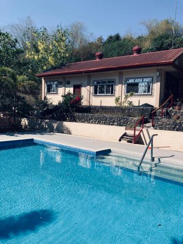 a swimming pool in front of a house at The poolhouse at McKirdy's mango farm in Sison