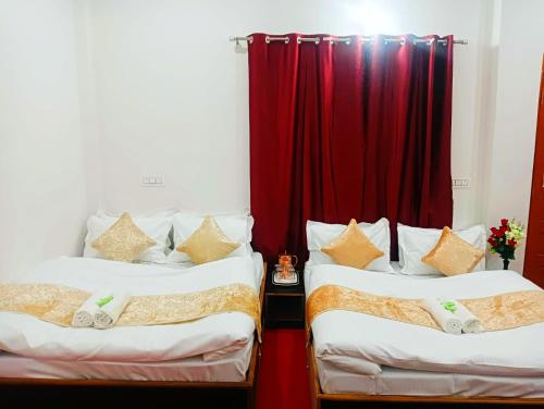 two beds in a room with a red curtain at Hotel Prakriti Darshan in Bhatwāri