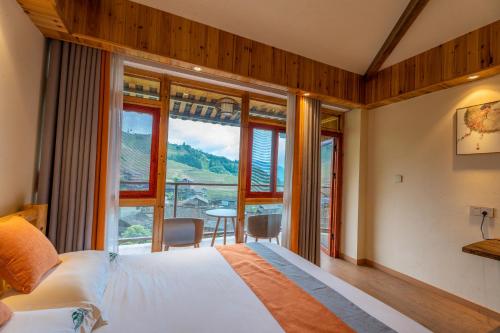 um quarto com uma cama e uma grande janela em 麦田间民宿Terrace View Hotel em Longsheng