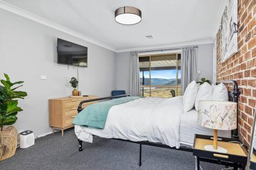 a bedroom with a bed and a brick wall at The Lakehaus at Lyell in Bowenfels