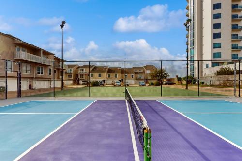 a tennis court with a net and some buildings at Mariner Village 307 in Seabrook