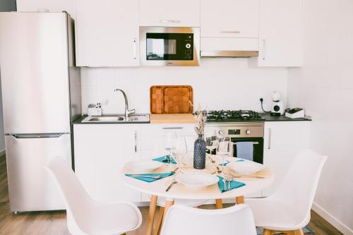 a white kitchen with a table and white chairs at VV La Niña - Salinetas -Telde in Las Palmas de Gran Canaria