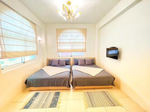 two beds in a room with a tv and windows at sea monkey diving homestay in Green Island
