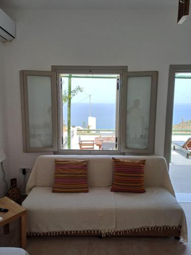 a couch in a room with a large window at G&O cycladic house with sea view! in Foinikiá