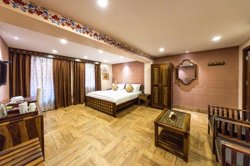 a bedroom with a bed and a table and a tv at Khamma Heritage in Jodhpur
