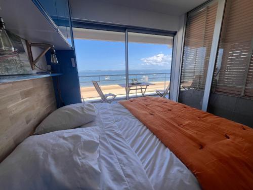 une chambre avec un lit et une vue sur la plage dans l'établissement Première ligne accès privé et direct à la plage Vue mer, à Arcachon