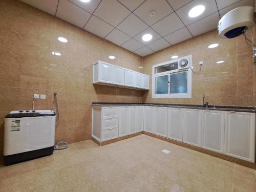 une grande cuisine avec des placards blancs et une fenêtre dans l'établissement فندق لامير إن Lamer in Hotel, à Sharurah